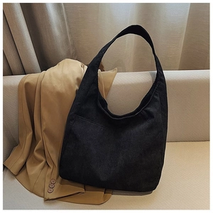 Nahaufnahme der schwarzen Cord-Einkaufstasche auf beigem Sofa mit Khaki-Blazer für Alltag