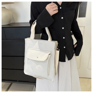 Detail of beige corduroy shoulder bag showing texture, strap, and front pocket on model
