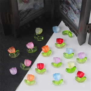 Detail of colorful glass tulip beads for DIY jewelry with vibrant petals and green leaves