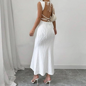 White backless maxi dress with textured fabric and cross tie details in a minimalist setting