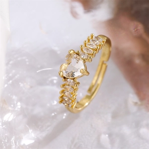 Macro shot of a gold-plated heart ring with sparkling zircons and marquise-cut side stones