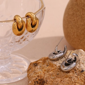 Detailed close-up of gold and silver geometric twisted earrings on textured props