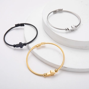 Detailed view of woven steel wire bracelets with cross charms in gold, silver and black