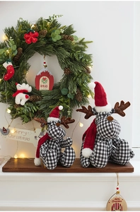 Detail of two black and white plaid reindeer plush dolls with red hats for Christmas decor
