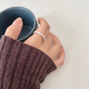 Detailed view of sterling silver ring with irregular hammered texture on model's hand