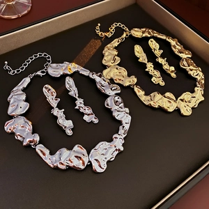 Detailed view of fluid irregular gold and silver necklace sets on a textured display tray