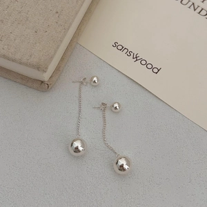 Macro detail of silver minimalist double ball dangle earrings with polished mirror finish