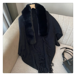 Close-up of black knit poncho featuring plush faux fur collar and elegant fringe details