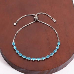 Adjustable silver tennis bracelet with 15 marquise-cut blue zirconias on a wooden stand