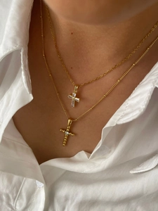 Layered gold cross necklaces with baguette and round zircons on model neck