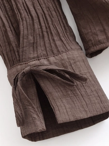 Detail der braunen Plissee-Ärmelmanschette mit verstellbarem Bindeband am Oberteil