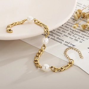 Elegant gold chain bracelet featuring three white pearls and lobster clasp on white tray