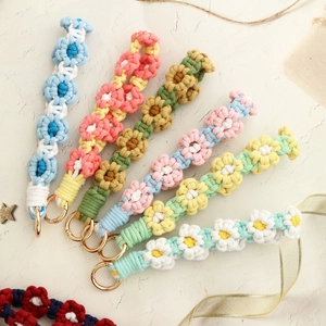 Macro view of macrame cotton flower wristbands with gold lobster clasps in various colors
