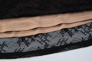 Detailed macro view of black lace fabric with nude lining and fine mesh stitching