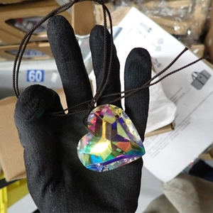 Macro shot of multifaceted crystal heart pendant reflecting colorful prism light effects