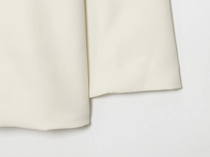 Détail rapproché du tissu de blazer croisé blanc crème avec texture tissée