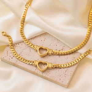 Golden heart-shaped titanium steel necklace and bracelet set on white silk and stone