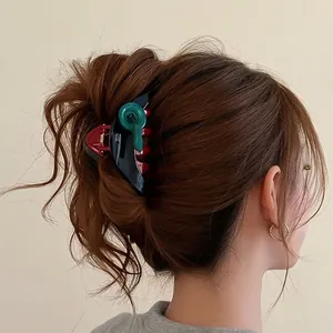 Black triangular shark hair clip with green and red button accents on female model