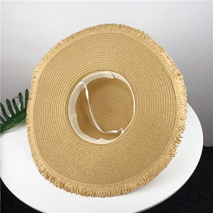 Detailed interior of wide brim straw hat with fringe edge and adjustable elastic strap