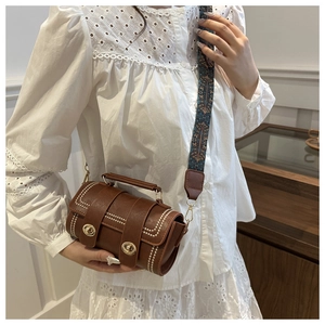 Brown Boston bag featuring white stitching and a vibrant wide ethnic woven strap