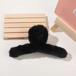 Close-up of large black plush hair claw clip on soft background for winter styling