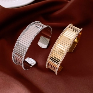 Dettaglio di bracciali placcati in oro 18 carati e argento con trama a righe e cristalli