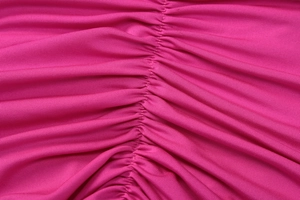 Makroaufnahme von leuchtend magentafarbenem Stretchstoff mit Raffung und Textur