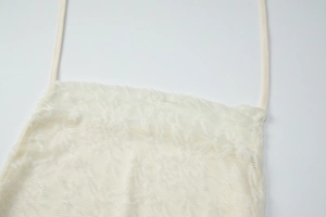 Detailed close-up of cream lace camisole showing textured fabric and thin straps