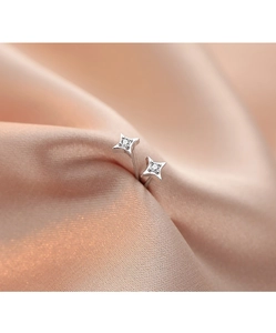 Close-up of S925 silver four-pointed star earrings with sparkling stones on silk