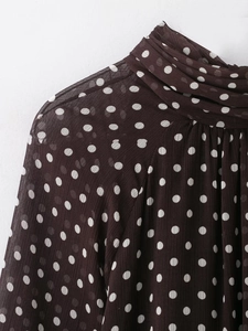 Dettaglio della camicia in popeline marrone a pois bianchi con collo alto a pieghe