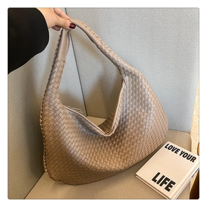 Close-up of beige woven leather hobo bag showing soft texture and handle on a chair