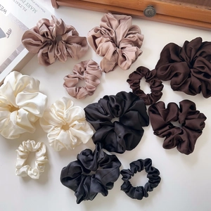 Assorted satin silk scrunchies in cream and brown tones displayed on a white background