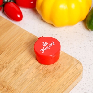 Close-up of a small red cartoon sauce bottle with a Happy crown lid on a wooden board