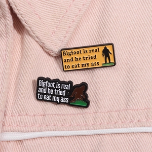 Close-up of enamel pins featuring Bigfoot silhouette on pink denim jacket fabric