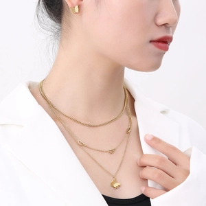 Detailed view of layered butterfly pendant necklaces and stud earrings on a model