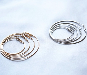 Set of gold and silver hoop earrings in three sizes displayed on silk fabric