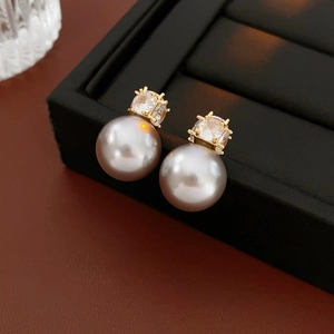 Detail of elegant pearl stud earrings with zircon inlay in a black jewelry box