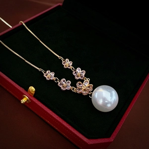 Close-up of pink zircon flowers and a large white pearl pendant on a gold chain