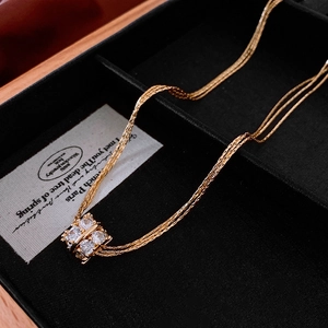 Detailopname van een vergulde meerlaagse ketting met een vierkante zirkonia-hanger