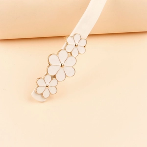 Macro shot of elegant white flower hair clip with golden metallic edges on soft background