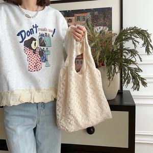 Close-up of cream white lace tote bag with delicate floral embroidery and mesh texture