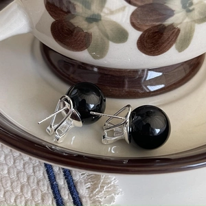 Minimalist 925 sterling silver hoop earrings with black agate beads on ceramic saucer
