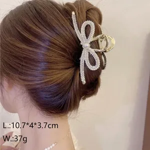 Elegant rhinestone bow claw clip with pearls in golden finish for hair styling