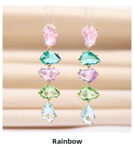 Macro shot of long drop earrings with five colorful teardrop stones in gold settings