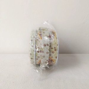 Detailed view of oval Easter tin box with vintage floral print in plastic packaging