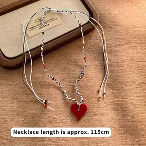 Detail of red heart pendant necklace with colorful woven cords measuring 115cm length