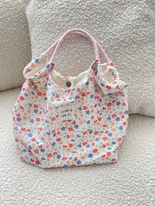 Macro detail of floral canvas tote bag featuring pink rope handles and snap closure