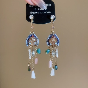 Détail des boucles d'oreilles ethniques à pompons avec cristaux et perles suspendues