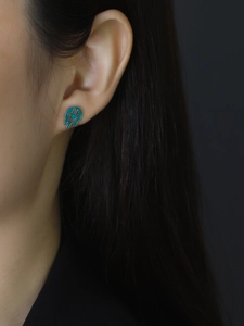 Detailed view of a model wearing a teal melting smiley face enamel S925 silver stud earring