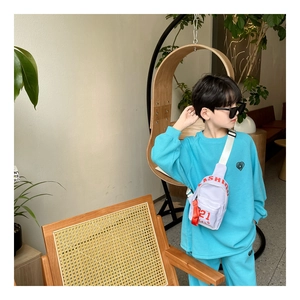 Détail d'un sac bandoulière blanc pour enfant avec imprimé rouge et fermeture éclair orange